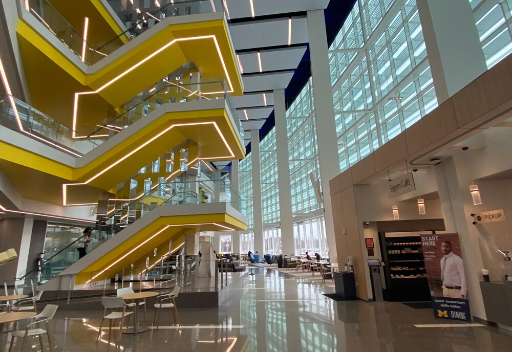 Interior lobby shown with floor to ceiling windows to the right and staircases to upper floors on the left.