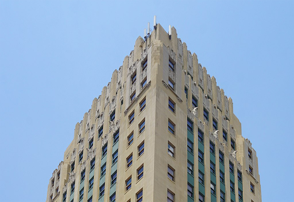 Corner photograph of the top of The Sinclair Hotel with a blue sky in the background.