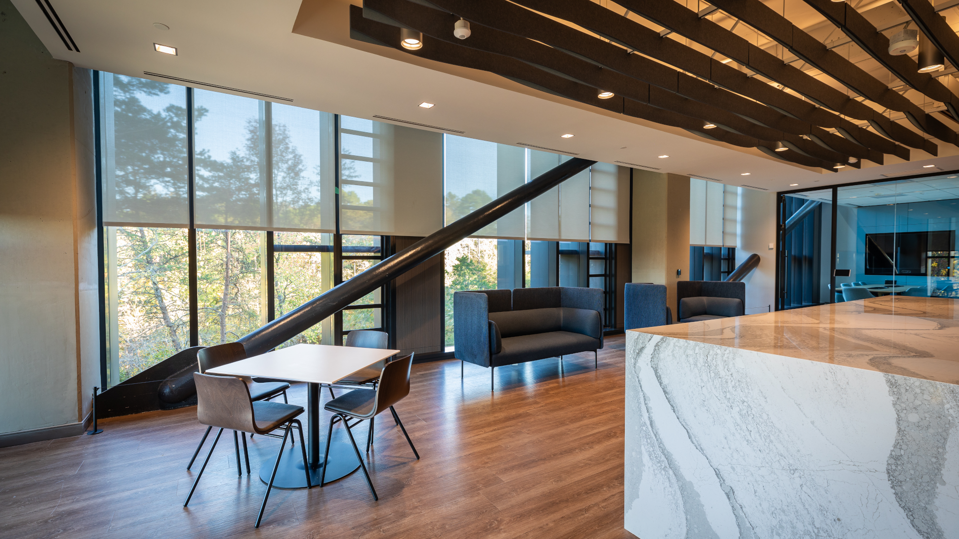 Vanguard Charlotte Campus' sitting area with couches and table positioned in front of open windows with shades partially lowered.
