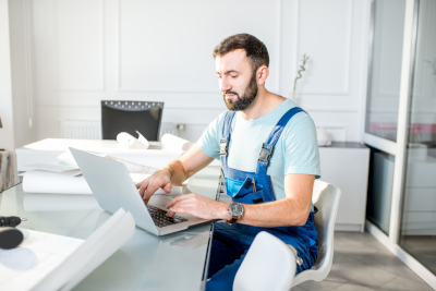 Somfy Expert using his laptop to contact sitting at a dining table.